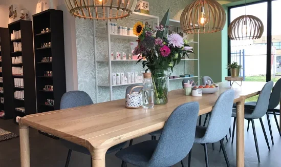 Showroom van Biocare Online met houten tafel, blauwe stoelen en productstellingen