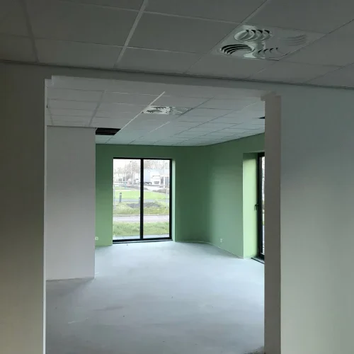 Lege ruimte in afbouw met groene wanden en een raampartij op de straat